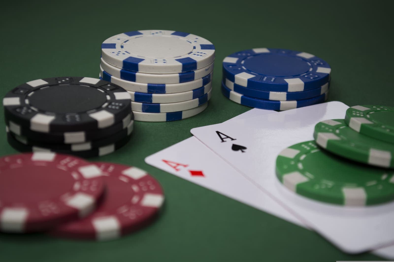 Stacks of casino chips beside a pair of aces on a green felt table